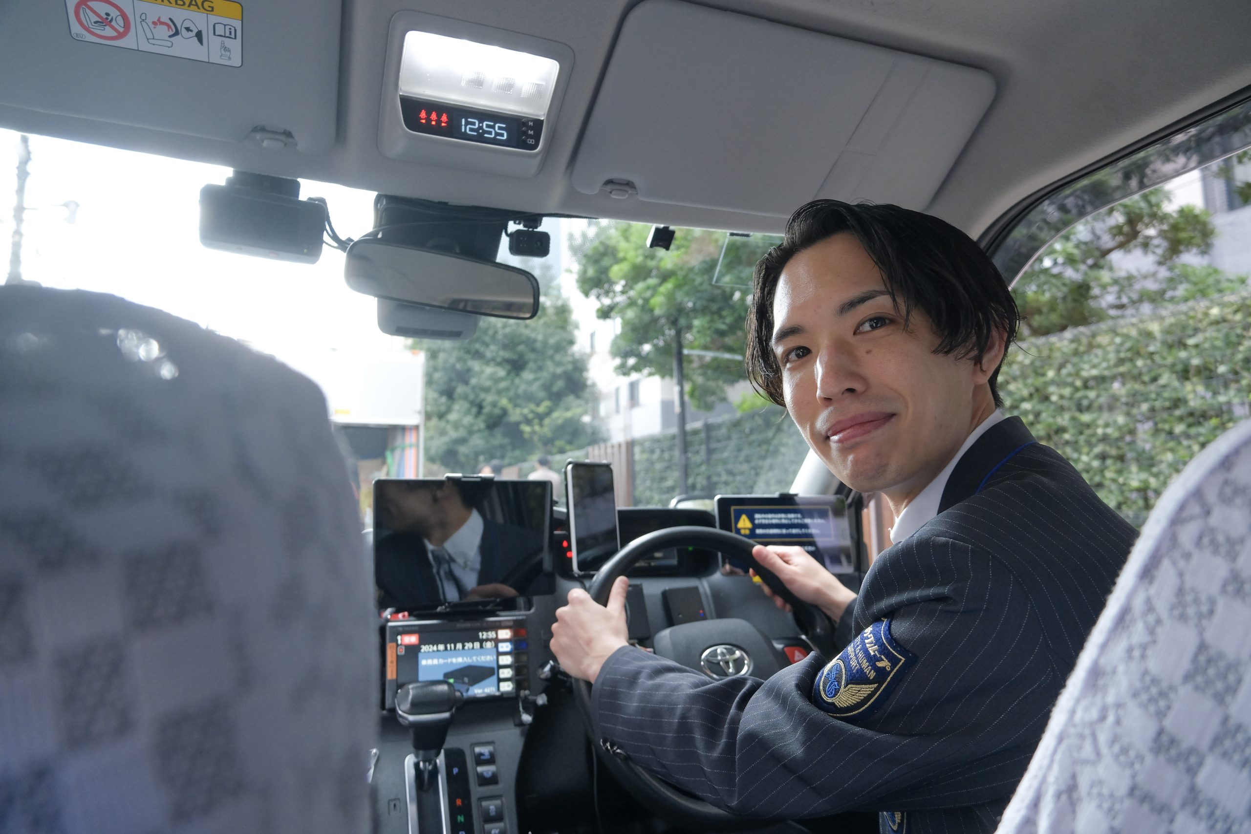 明るい車内で、お客様を見送った後に満足そうに微笑むドライバー。