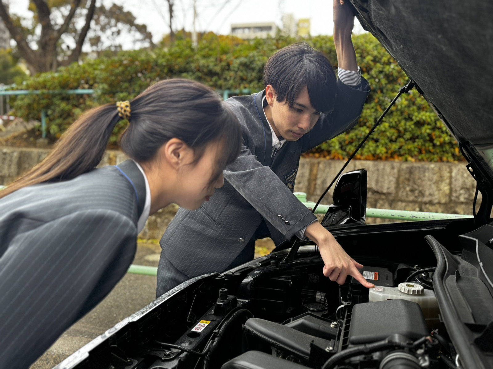 屋外で研修を受ける日本人の若手ドライバーと先輩。サポートを受けながら成長する姿を描いた写真。