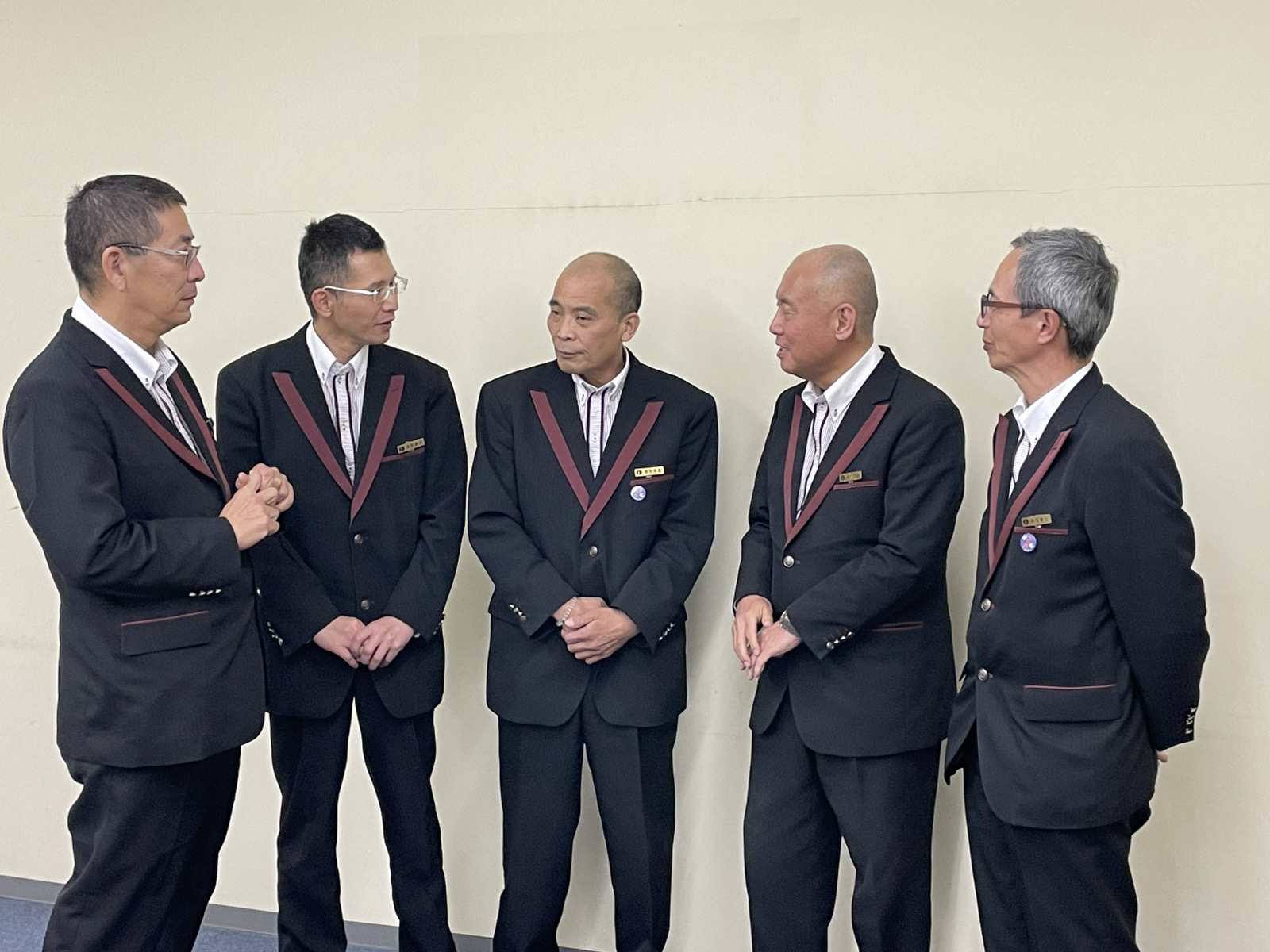 オフィスラウンジで会話する複数の日本人タクシードライバー。和やかで信頼関係を感じる社内の雰囲気を表現。