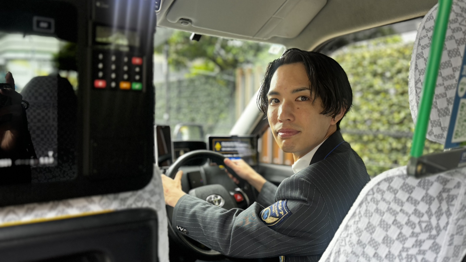 お客様を送り届けた後に笑顔を見せるタクシードライバー