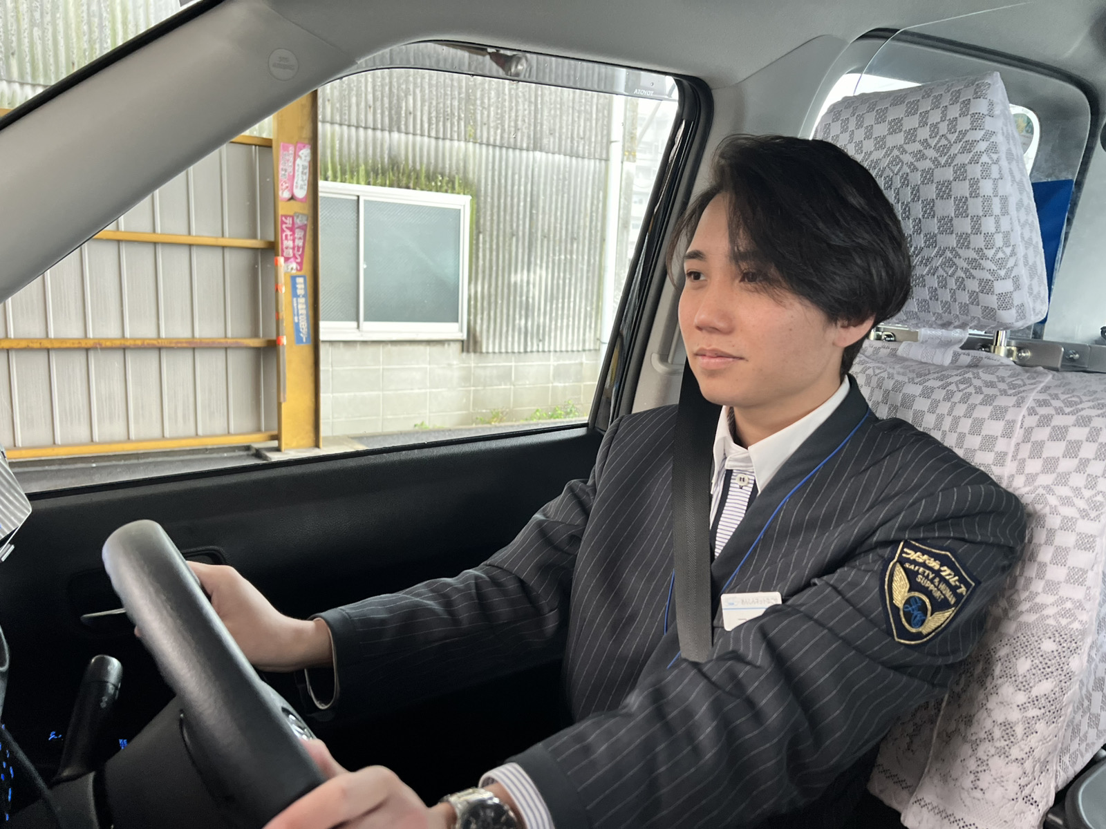 黒色のタクシーの前で笑顔で立つ30代男性ドライバー。未経験者を支えるつばめタクシーグループのイメージ